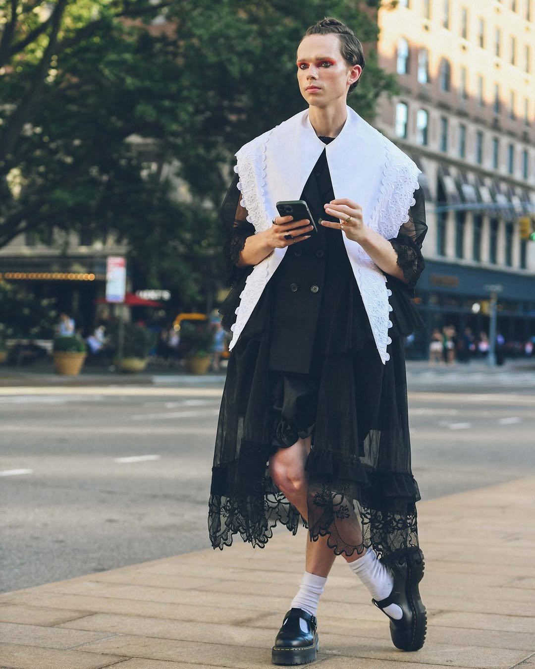 A black sheer lace midi look is layered with an oversized white embroidered bib collar, white socks, and chunky black Mary Jane shoes.